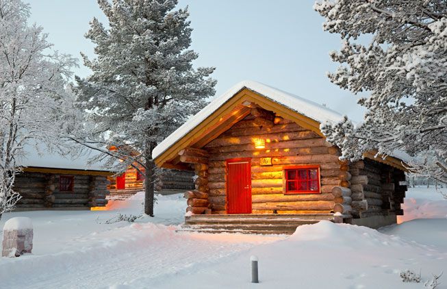 Cabin in the woods with a snowy roof and red door
