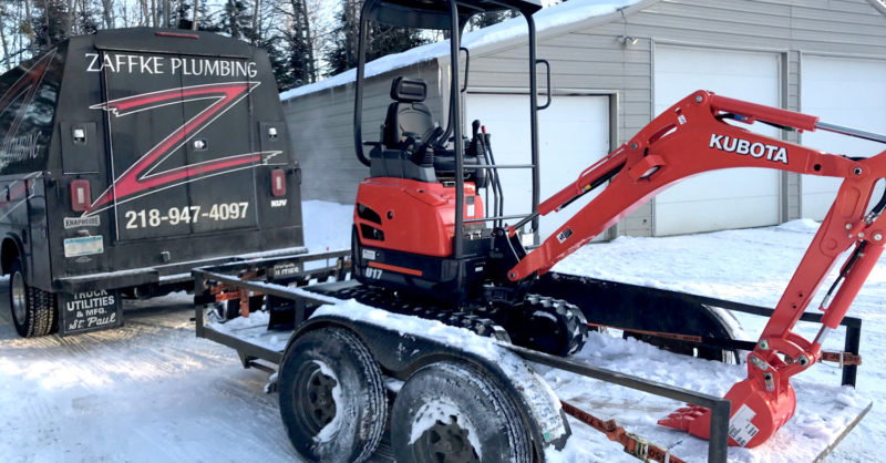 Excavator on a trailer attached to Zaffke Plumbing truck